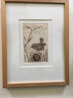 Full view of framed and matted print featuring a wren bird on a stump with a round object beneath.