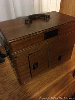 Wooden case with handle on top for the vintage EKG machine, showing front and top side.