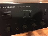 Front panel showing Onkyo Integra logo, power buttons, subsonic filter, loudness, tone controls, balance knob, speaker selector, and headphone jack.