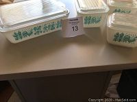 Photo showing the 8 piece vintage Pyrex set with white glass dishes decorated in green floral pattern and clear ribbed lids.