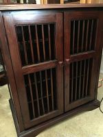 Front view of dark wood liquor cabinet with vertical slat double doors and round knobs
