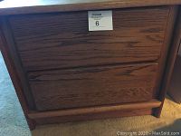 Photo showing oak nightstand back and part of side with natural wood finish and two drawers