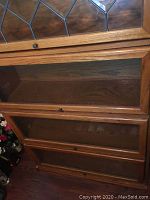 Close-up of stacked compartments with glass paneled doors showing wood grain and door handles.