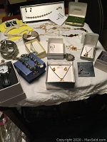 Full overview of the jewelry lot showing multiple necklaces, bracelets, earrings, and brooches arranged on a table, some in jewelry boxes.