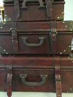 Front stacked view showing the three faux leather trunks stacked on top of each other with visible black handles, straps, and buckles