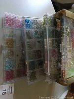 Top view of plastic compartment organizer trays filled with assorted beads in multiple colors and sizes.