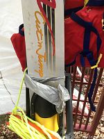 Close-up photo showing silver and black adult water ski with 'Cut'n Jump' logo, yellow binding, and bright yellow tow rope secured around the ski.