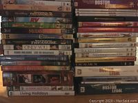 Photo of assorted DVDs stacked showing various movie and TV series titles including several Boston Legal seasons and animated movies.