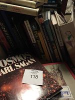 Photo showing an assortment of books including 'Cosmos' by Carl Sagan and religious and cooking titles.