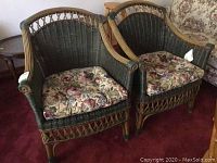 Two matching wicker chairs side by side with floral seat cushions on a red carpet