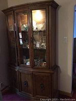 Front view of wooden display cabinet showing glass doors with display items inside and lower storage cupboards.