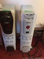 Front view of two oil-filled radiator heaters side by side with visible control panels and labels