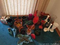 Full view of assorted glass and pottery vases in various colors and styles on blue carpet.