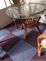 Full view of square glass table top on bamboo base with chairs surrounding it.