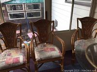 Set of three bamboo chairs with upholstered seat pads placed indoors near window and glass table visible.