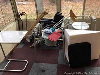 Photo showing wide view of Ride-lite 9000 wheelchair with crutches, canes, commode, overbed tables and cushions grouped together