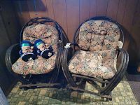 Pair of wood framed chairs with floral cushions and pair of Toronto Maple Leaf novelty slippers on one chair.