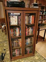 Front view of wooden bookcase with glass doors showing multiple shelves and items inside.