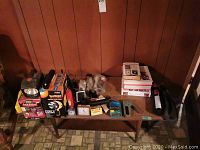 Full view of table with all items present including flashlights, books, clocks, and various small tools.