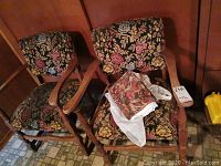 Pair of wood framed chairs with floral patterned upholstery, showing sides and arms.