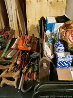 View of various hand tools including saws and screwdrivers laid out with metal hand plane and some boxed hardware items.