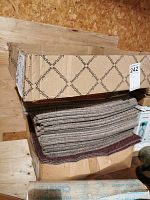 Box with carpet tiles stacked with visible pattern and brand InterfaceFLOR on box