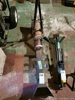 Full view of hydraulic log splitter showing metal frame, handles, hydraulic piston and wedge area for splitting logs.