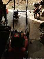 Front view of the red Yard Machines push lawn mower showing handlebar, wheels, and engine cover.
