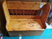 Front view of wooden bench showing spindled backrest and curved armrests.