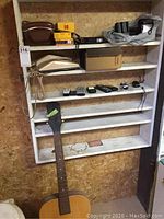 Full shelf view showing all items: top View-Master and film boxes; second shelf phone; third shelf cell phones and chargers; floor guitar.
