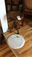 Photo showing the wood pedestal table with a detached round marble top on the floor next to it.