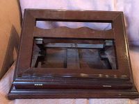 Top view of closed wooden music or book stand showing polished dark wood frame and glass or clear insert.