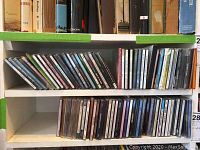 Photo showing two shelves filled with CDs arranged horizontally and vertically compactly.