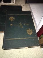 Two green hardcover volumes with gold embossed seals on the front covers.