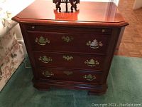 Front view showing three drawers, brass hardware and beveled top