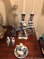 Assorted Delft ceramics including candlesticks, windmill, miniature houses and cheese dome on wooden table