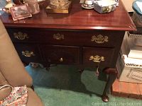 Front view of mahogany side table showing polished top and brass hardware