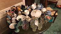 Overview photo showing the collection of dishes, goblets, figurines, and candleholder on a round table.