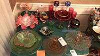 Overview of glass bowls and candy dishes including Fenton pink bowl, green depression glass, pink and red glass items