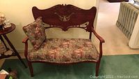 Full view of the vintage wooden settee showing the carved backrest and the patterned upholstered seat with matching cushion.