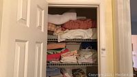 Closet shelves showing folded towels, linens, and sheets in various colors and patterns.