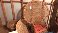 Peacock-style wicker armchair with cushion leaning against wall