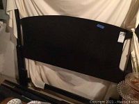 Photo showing the dark finished curved headboard with tags attached