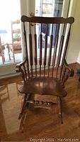 Full front view of vintage wood rocking chair showing vertical back spindles, contoured seat, and armrests