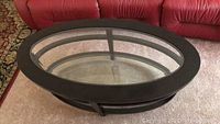 Top view of the oval coffee table showing two clear glass inserts embedded in wood composite frame on carpeted floor.