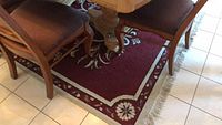 Dining room area rug partially visible under dining table and chairs, showing burgundy base and floral pattern in cream with border.