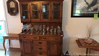 Photo of solid maple wood hutch bottom showing glassware on top, with multiple drawers and cabinet doors below.