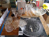 Overview of various glassware items including six etched glasses, candlesticks, bowls, boxed champagne flutes, and a boxed etched glass platter on a wooden surface.