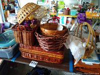 Group of woven baskets in different sizes and shapes including handle, utensil and napkin holders shown on table.