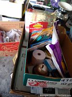 Top view of box containing various office supplies including packages of 3M Command strips, pens, and small items in a cardboard box labeled 'Classic Linen'.